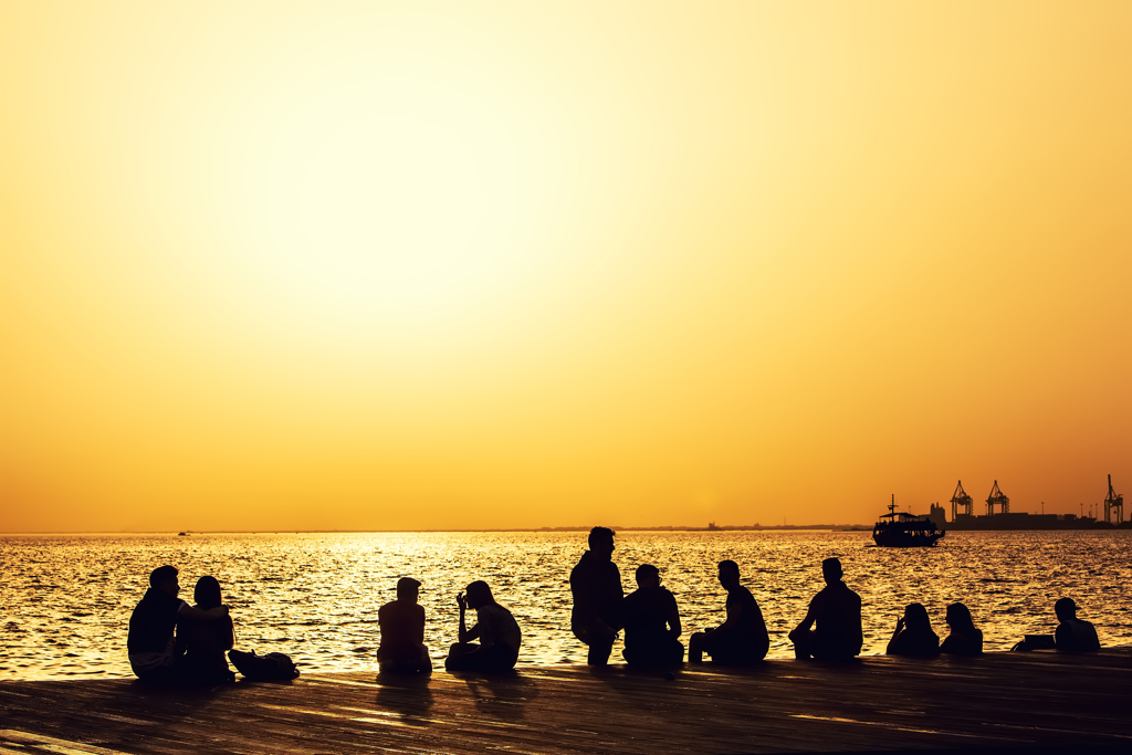 Silhouetten van mensen op een pier bij zonsondergang aan zee in Noord-Griekenland.