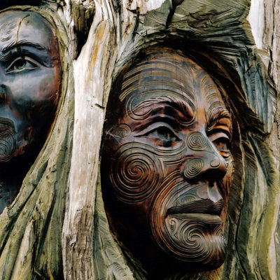 Houtsnijwerk met Māori-gezichten en traditionele patronen tijdens een groepsrondreis Nieuw-Zeeland.