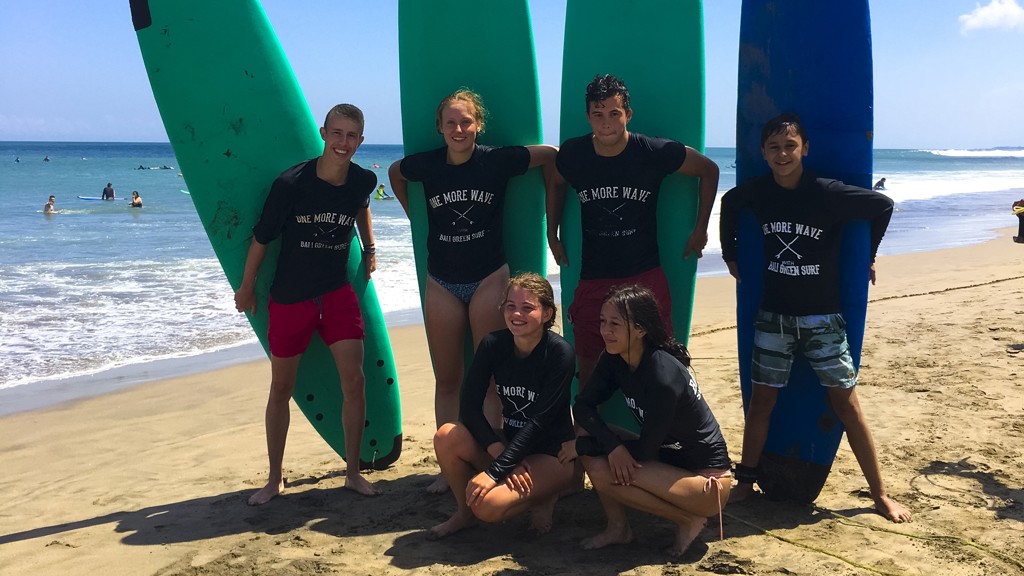 Gezin met surfboards op het strand tijdens familiereis Sumatra, Java en Bali.