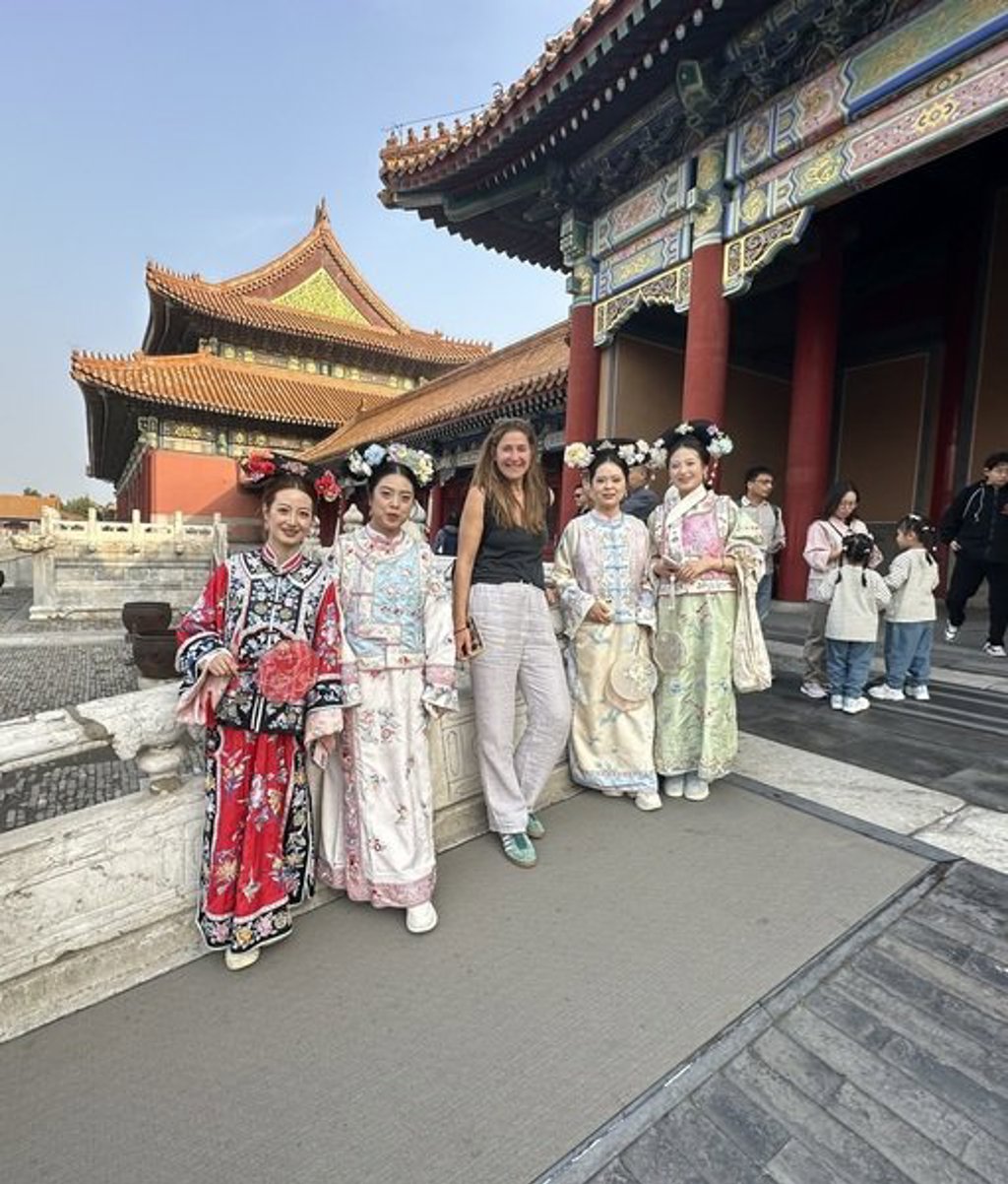 Groepsrondreis China: reiziger poseert met vrouwen in traditionele kleding bij een tempelcomplex in Beijing.
