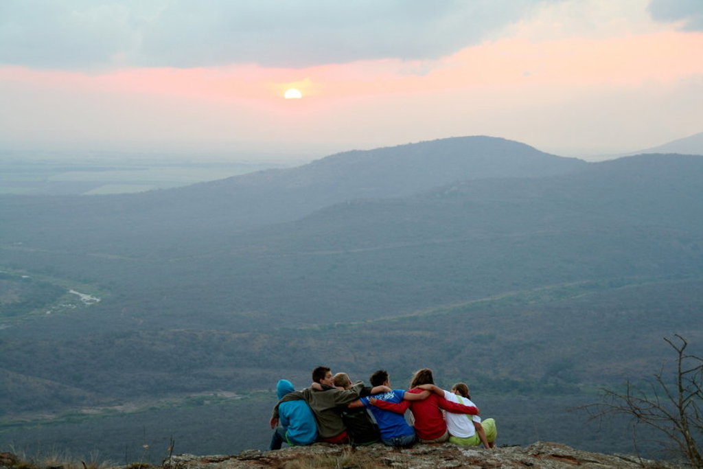 Gezin kijkt bij zonsondergang uit over bergen in Zuid-Afrika tijdens familiereis naar eSwatini.