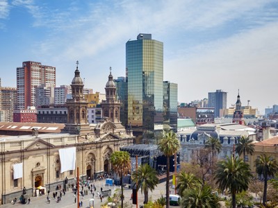 Uitzicht op Plaza de Armas in Santiago de Chile met historische gebouwen, palmbomen en moderne skyline.