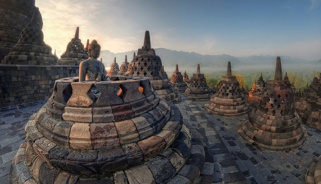 Zonsopkomst bij Borobudur-tempel op Java, met boeddhabeeld en stoepa’s tijdens groepsrondreis Java & Bali.