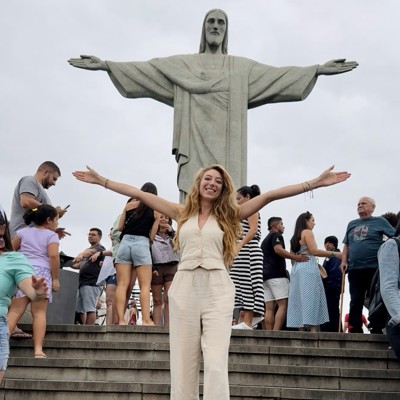 Reiziger poseert met gespreide armen bij Christus de Verlosser in Rio de Janeiro tijdens een 22-35ers reis Brazilië.