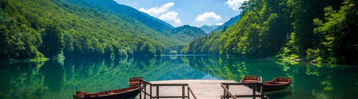 Uitzicht over een bergmeer met houten steiger en bootjes in Bosnië en Herzegovina.
