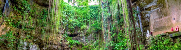 Zwemmen in Cenote Ik Kil, een open kalksteengrot met hangende lianen en helderblauw water bij Chichén Itzá, Mexico.