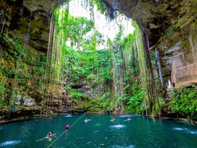 Zwemmen in Cenote Ik Kil, een open kalksteengrot met hangende lianen en helderblauw water bij Chichén Itzá, Mexico.