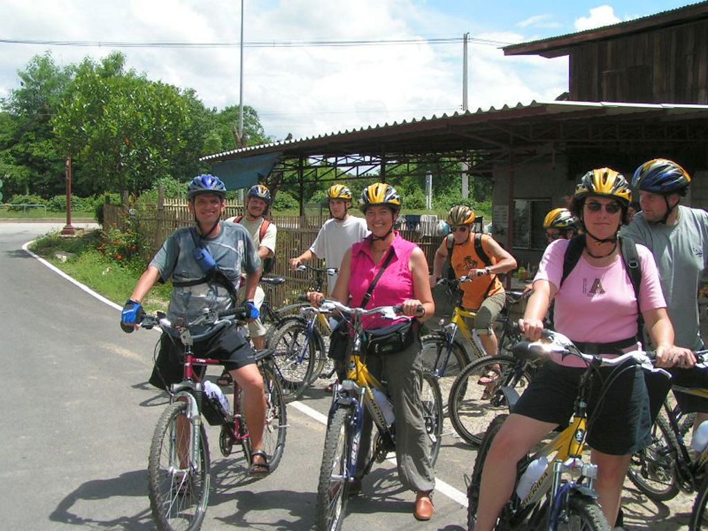 Groep reizigers op de fiets tijdens groepsrondreis Thailand Hoogtepunten, bij een dorp langs de weg.