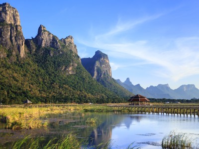 Uitzicht op kalkstenen bergen en een houten vlonderpad bij een meer in Thailand, Route Thailand.