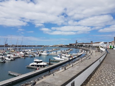 Jachthaven van Ponta Delgada op São Miguel, Azoren, met boten en boulevard onder een blauwe lucht.