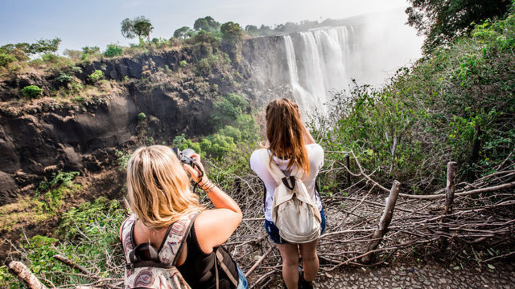 22-35ers bewonderen en fotograferen de Victoria Falls tijdens een groepsrondreis door Zuidelijk Afrika.