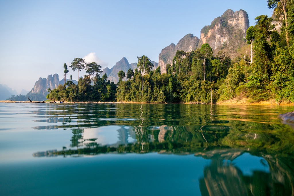 Groene jungle en kalkstenen rotsen weerspiegeld in een rustig meer tijdens Familiereis Thailand Chill & Adventure.