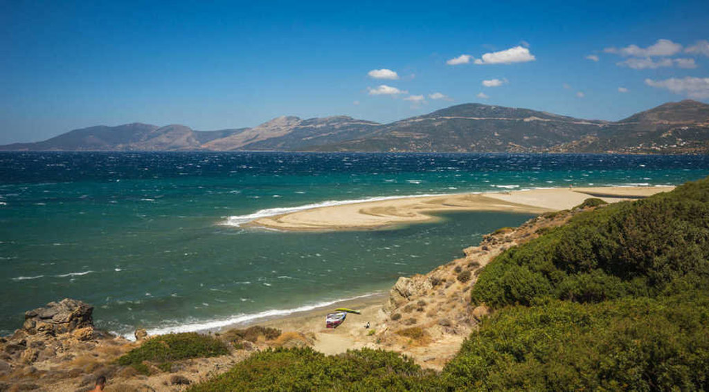 Zandstrand en lagune aan de kust van Evia, Griekenland, met bergen op de achtergrond.