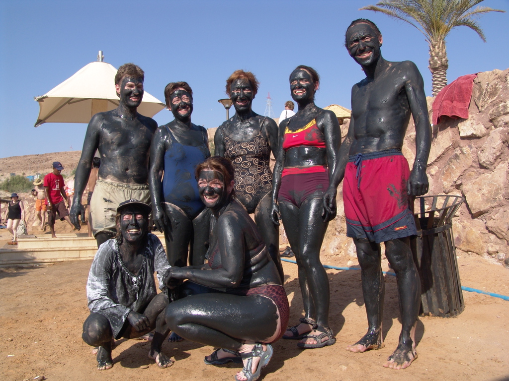 Groepsreis Jordanië: reizigers onder de modder bij de Dode Zee, lachend op het strand.