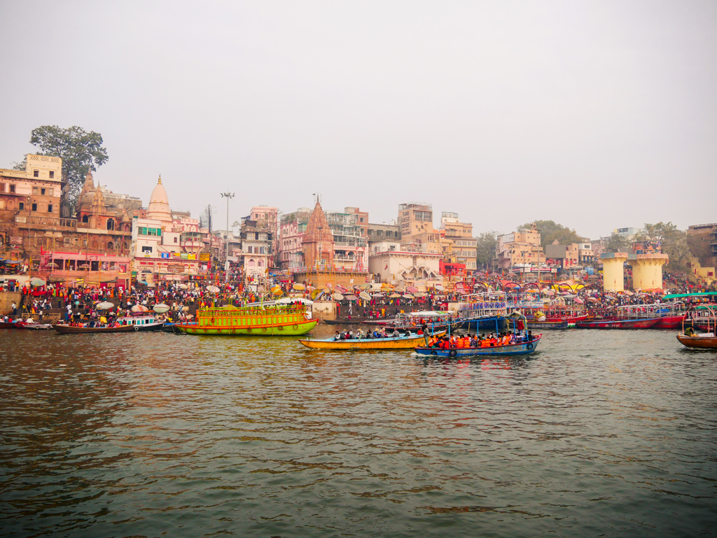 Drukke ghat aan de Ganges in Varanasi met boten en tempels tijdens een 22-35ers reis India.