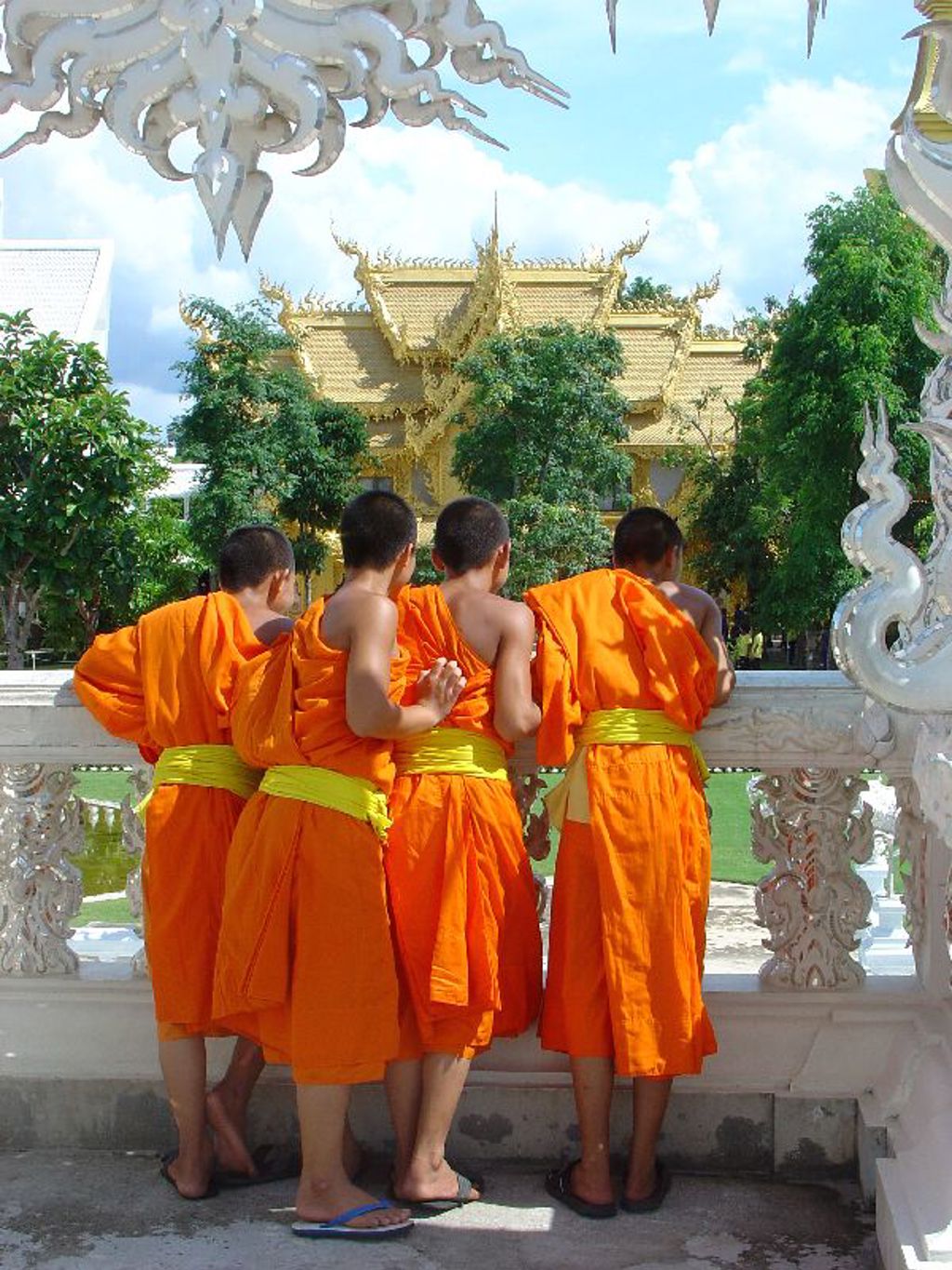 Monniken in oranje gewaden bij een gouden tempelcomplex in Thailand.