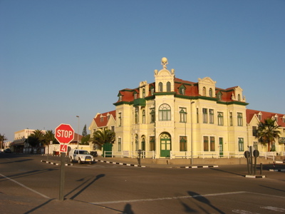 Historisch gebouw in Swakopmund, Namibië, met rood dak en stopbord op een kruispunt.