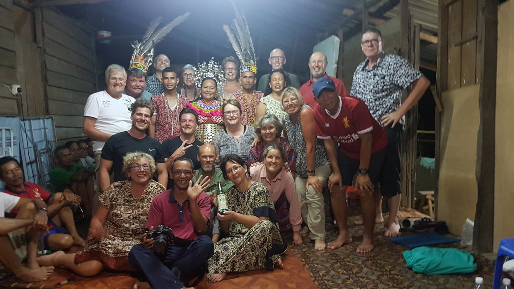 Groepsfoto van reizigers met lokale bewoners in traditioneel kostuum tijdens groepsrondreis Maleisisch Borneo.