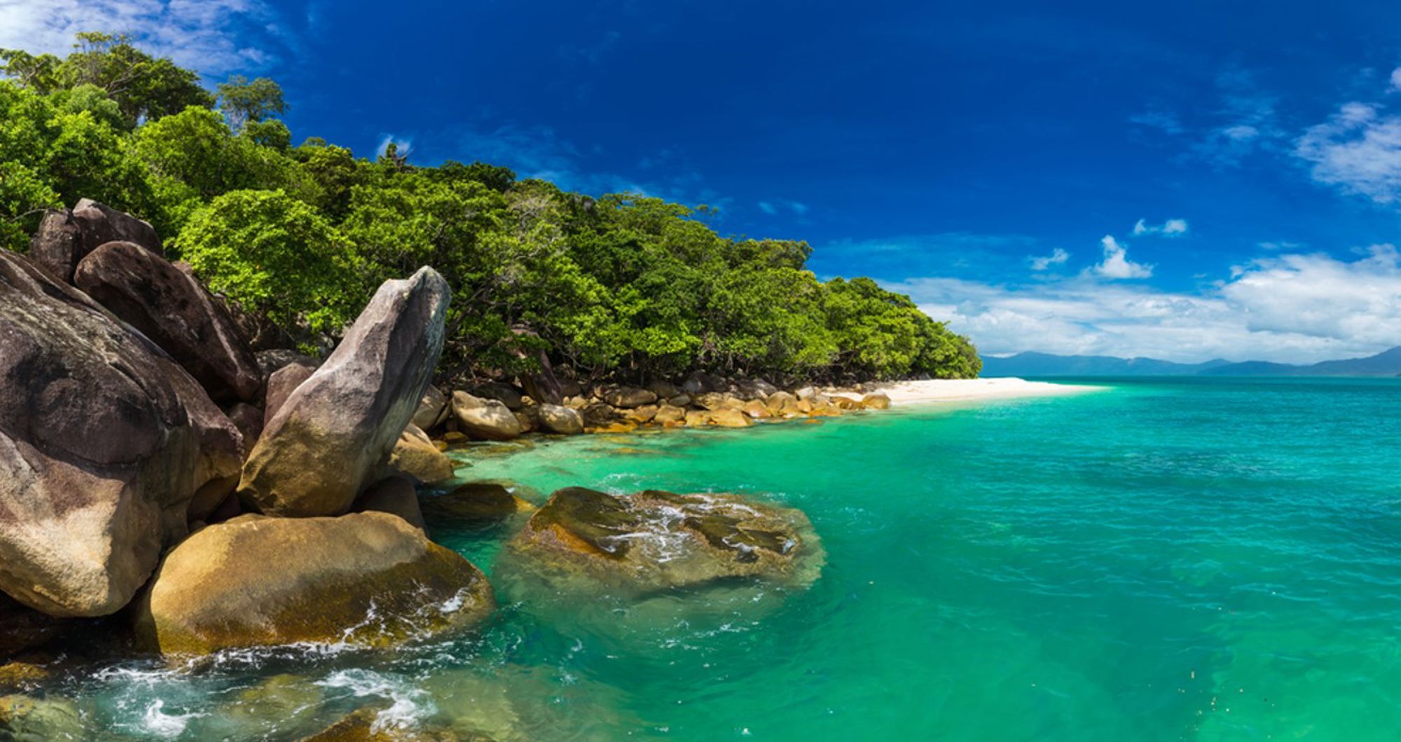 Tropisch strand in Australië met granieten rotsen, groen regenwoud en helder turquoise water.