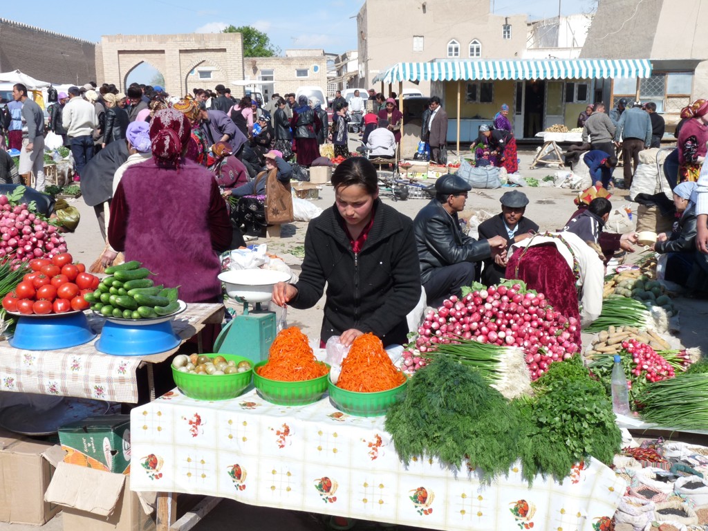 Drukke markt op de Zijderoute met kramen vol groenten en kruiden.