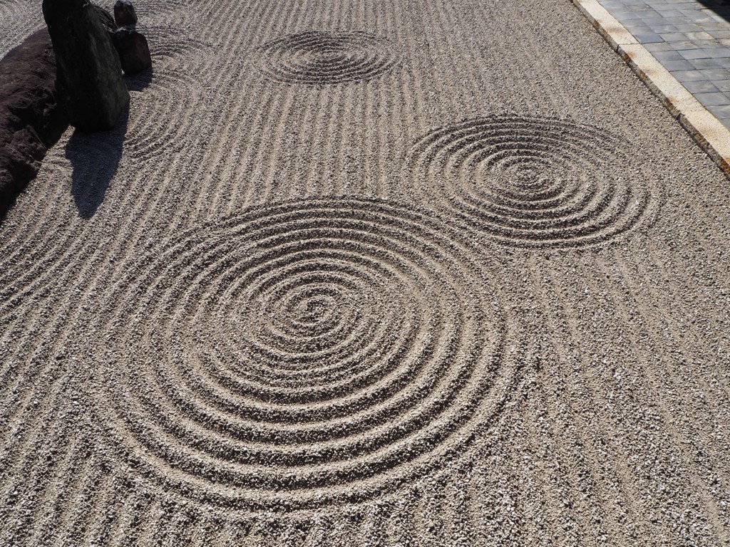 Zen-tuin in Japan met geharkt grind en concentrische cirkels rond stenen.