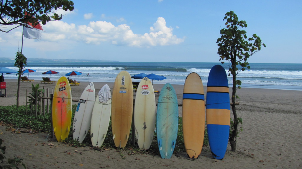 Surfplanken op het strand van Bali met golven op de achtergrond.