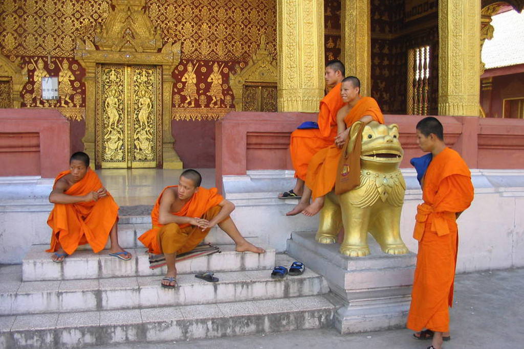Boeddhistische monniken bij een rijkversierde tempel in Laos tijdens groepsrondreis Laos en Cambodja.