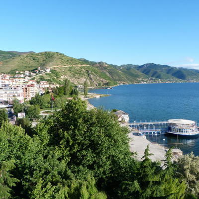 Uitzicht op Pogradec aan het Ohridmeer met boulevard en bergen, tijdens groepsrondreis Albanië, Kosovo en Noord-Macedonië.