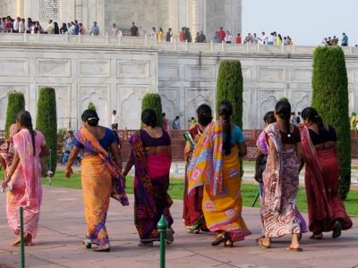 Vrouwen in kleurrijke sari’s wandelen bij de Taj Mahal in Agra.