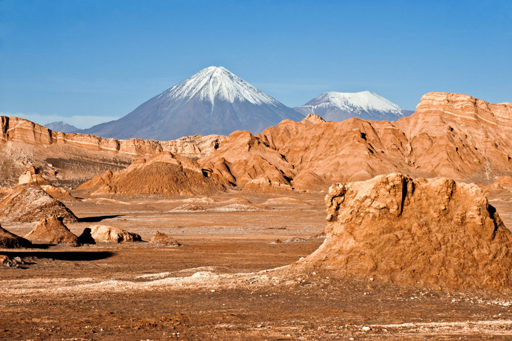 Woestijnlandschap bij San Pedro de Atacama met rotsformaties en besneeuwde vulkanen in Chili.