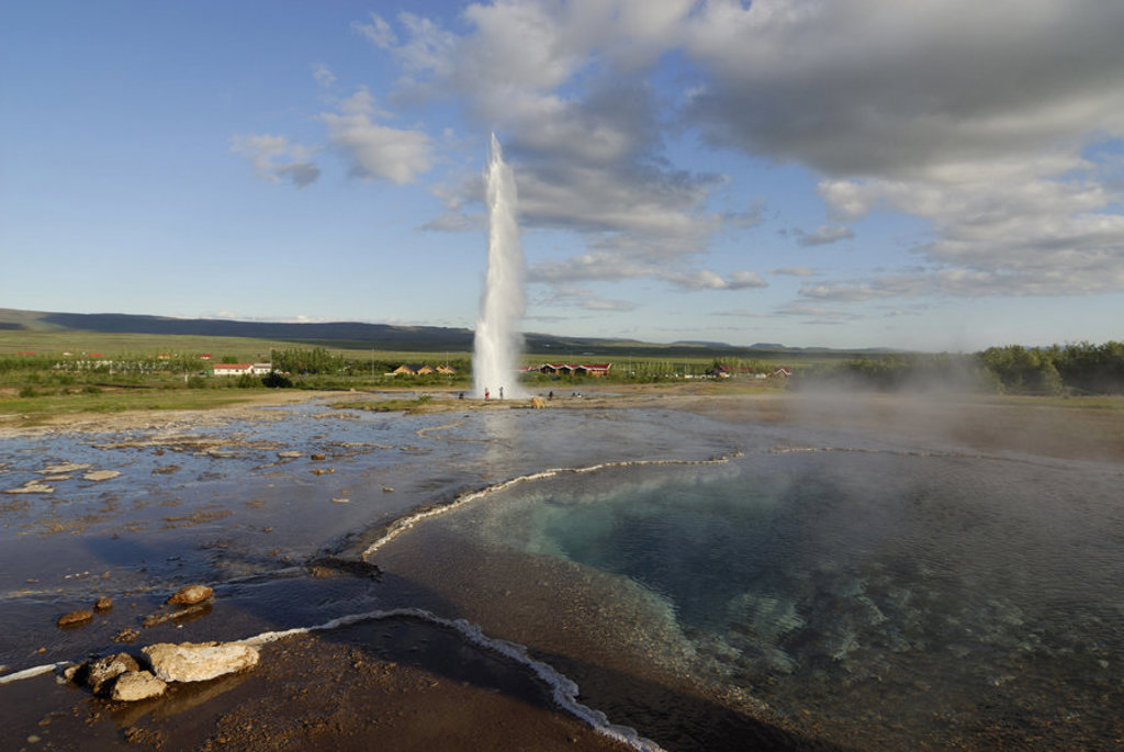 Geyser die hoog de lucht in spuit in het geothermische landschap van IJsland tijdens een groepsrondreis.