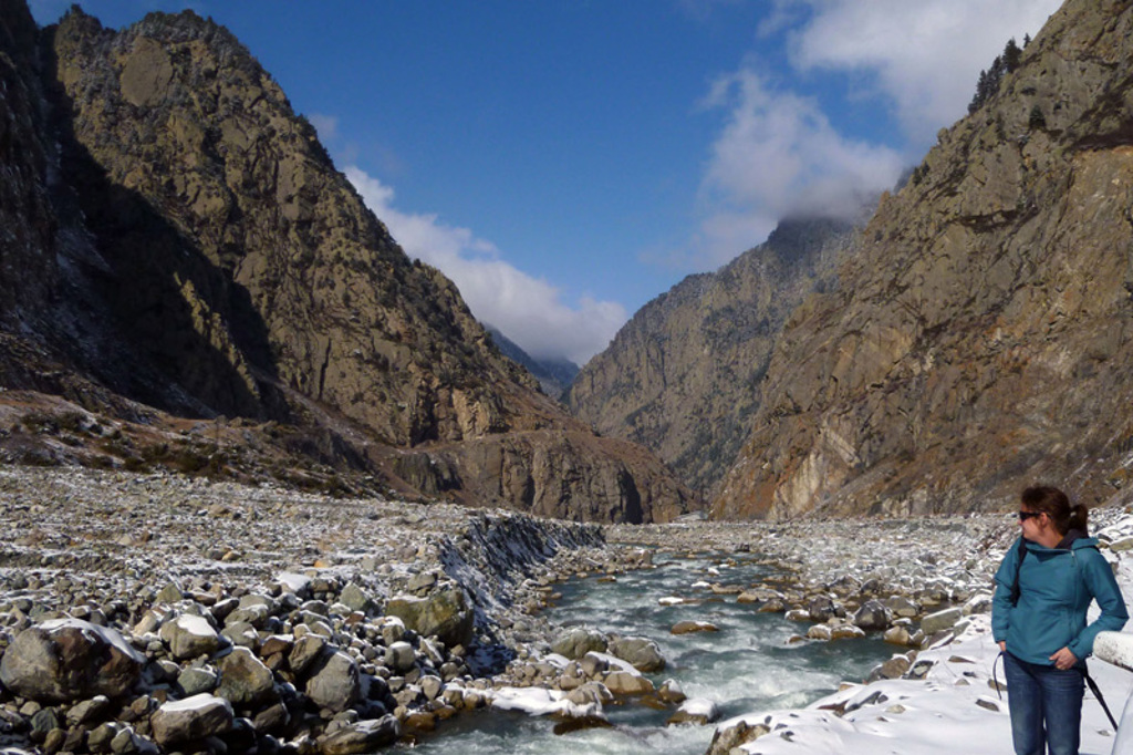 Wandelaar bij een rivier in een besneeuwde bergkloof in Georgië tijdens een 22-35ers groepsrondreis.