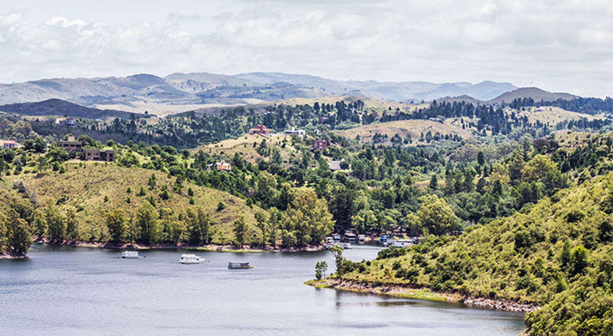 Landschap Cordoba Uitzicht op een meer met boten, groene heuvels en bergen in Argentinië.
