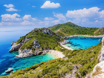 Uitzicht op een turquoise baai met strand en groene rotsen langs de kust van Noord-Griekenland.