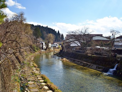 Rivier door Japans bergdorp langs huizen en bosrand, Route Japan.
