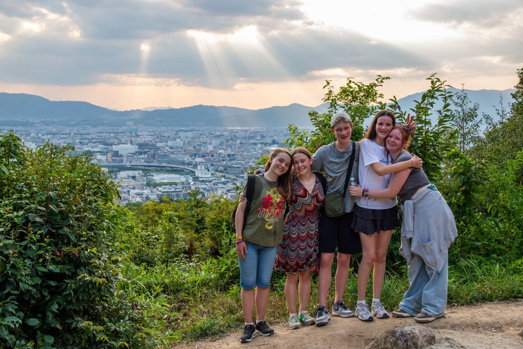 Gezin op uitzichtpunt met panorama over Kyoto tijdens familiereis Japan.