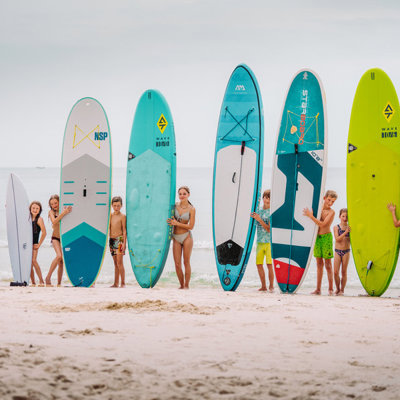 Kinderen met surf- en SUP-boards op het strand tijdens een familiereis Thailand Hoogtepunten.