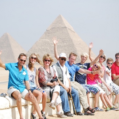 Gezin op familiereis in Egypte poseert bij de piramides van Gizeh.