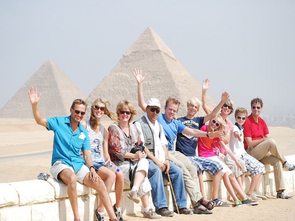 Gezin op familiereis in Egypte poseert bij de piramides van Gizeh.