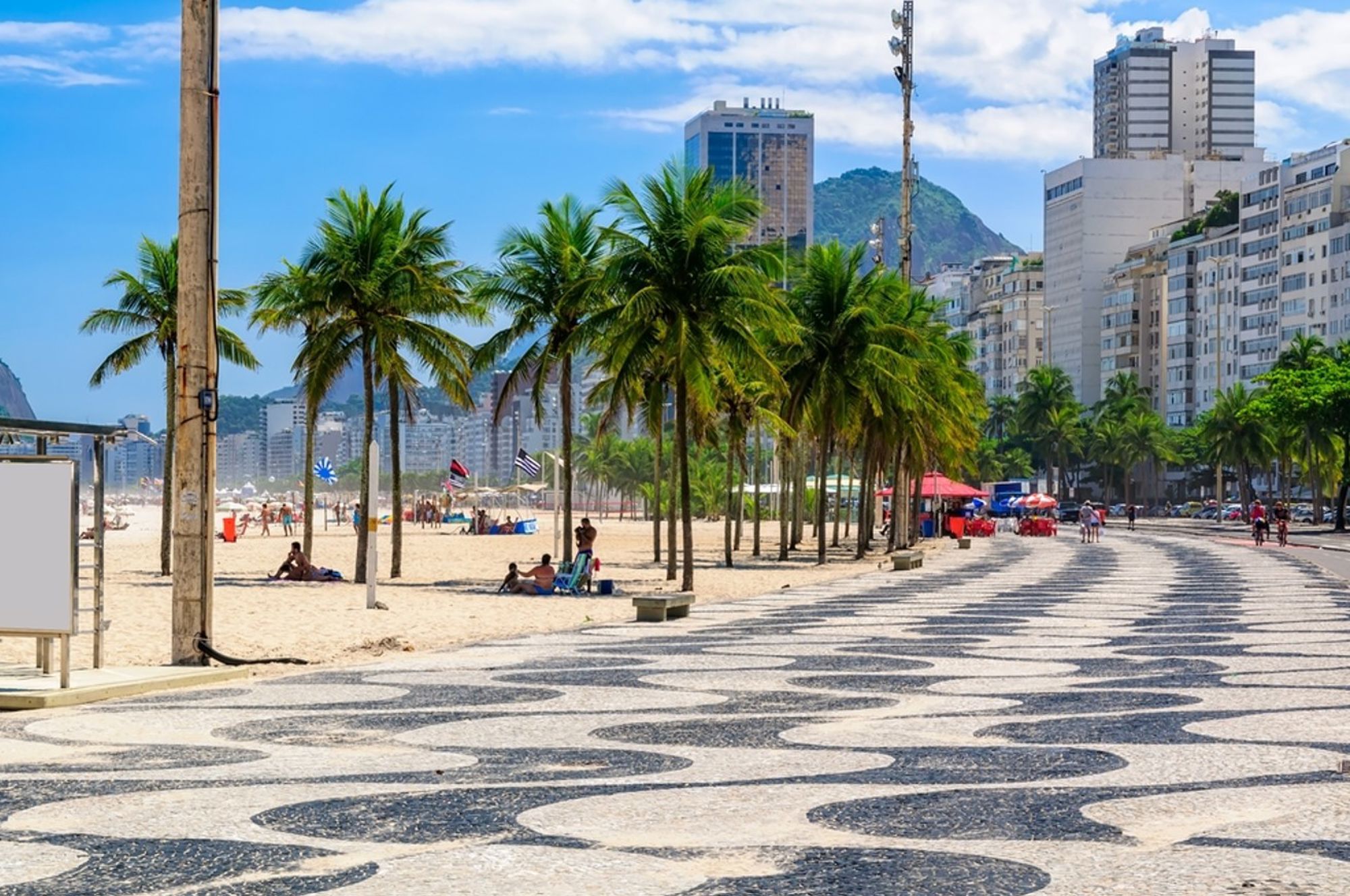 Boulevard met golvend mozaïek, palmbomen en strand bij Copacabana in Rio de Janeiro, Brazilië.