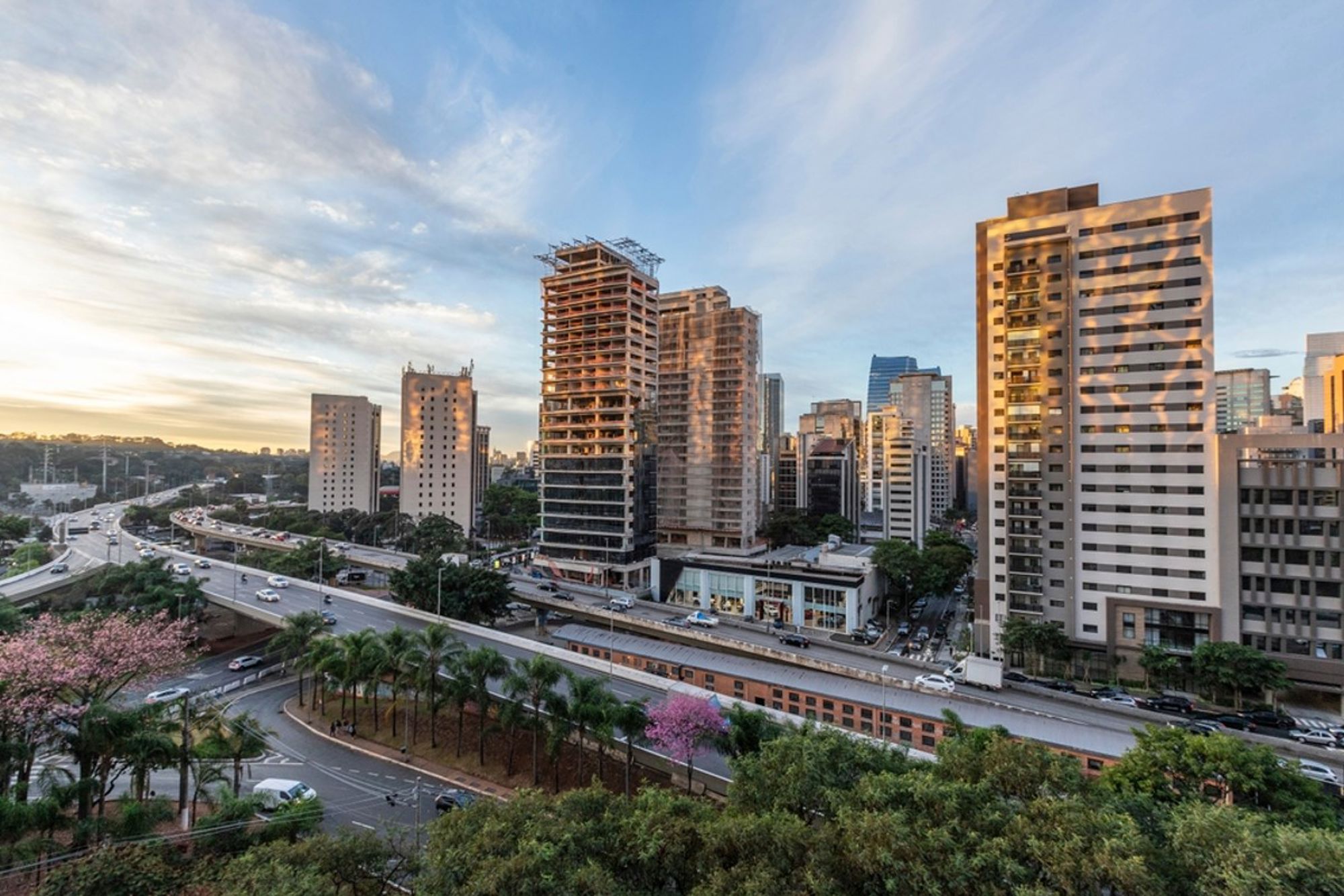 Skyline van São Paulo met hoge gebouwen en drukke snelweg bij zonsondergang.