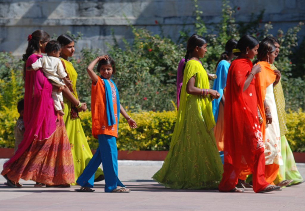 Vrouwen en kinderen in kleurrijke kleding lopen over straat tijdens een familiereis in India en Nepal.