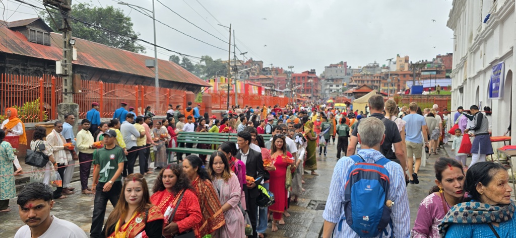 Drukke straat bij een tempelcomplex tijdens een festival in Nepal, met pelgrims en reizigers.