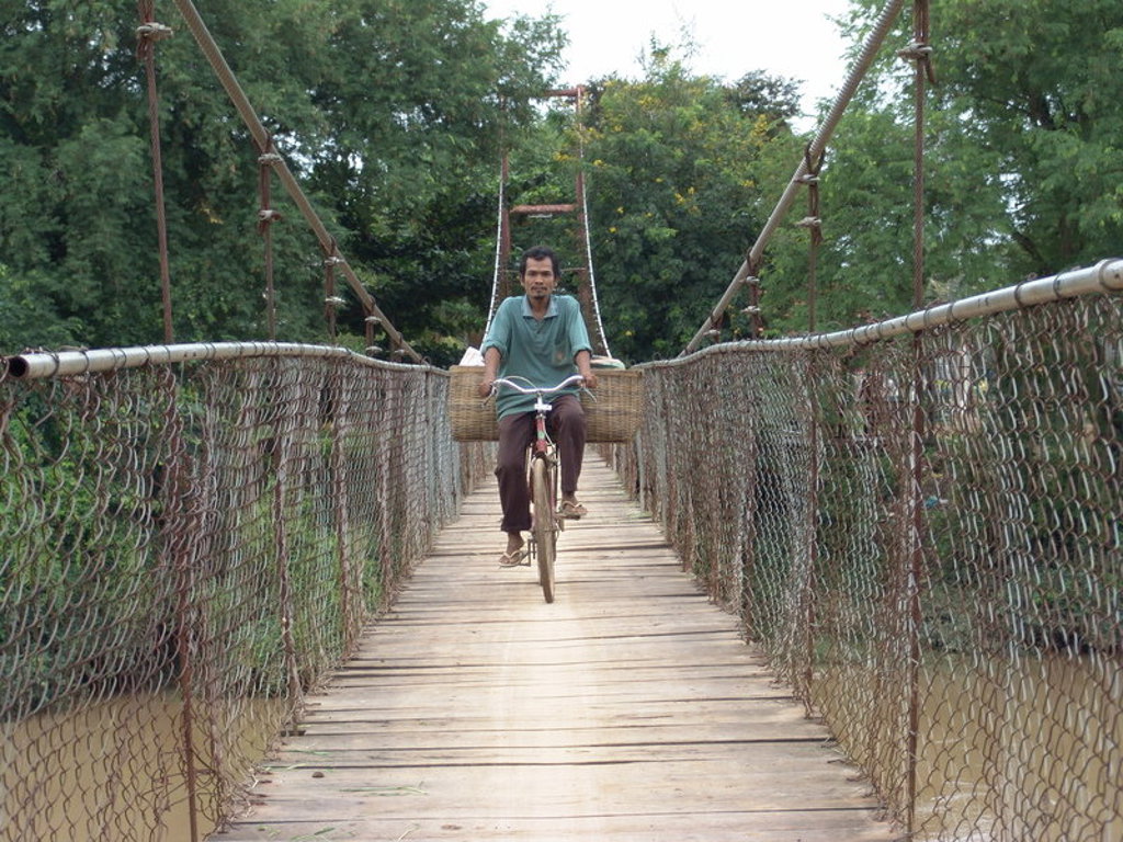 Fietser steekt een hangbrug over tijdens fietsvakantie in Vietnam, Cambodja en Thailand.