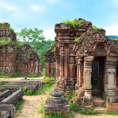 Ruïnes van het My Son tempelcomplex in Vietnam, met bakstenen torens en poort tussen groen.
