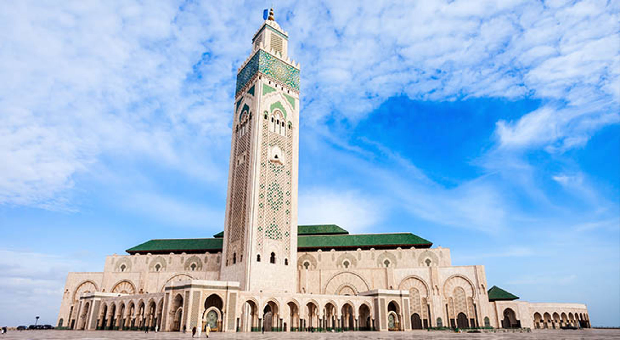 Hassan II-moskee in Casablanca, Marokko, met hoge minaret en mozaïekdetails onder een blauwe lucht.