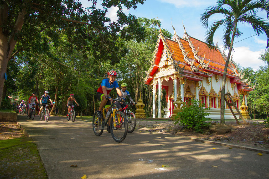 Fietsers passeren een boeddhistische tempel tijdens fietsvakantie Vietnam, Cambodja en Thailand.