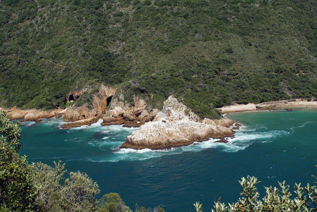 Rotsachtige kust en turquoise zee langs de Tuinroute in Zuid-Afrika.