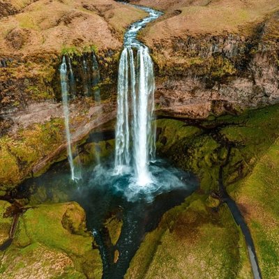 Waterval in een groen, rotsachtig landschap in IJsland tijdens een groepsrondreis.