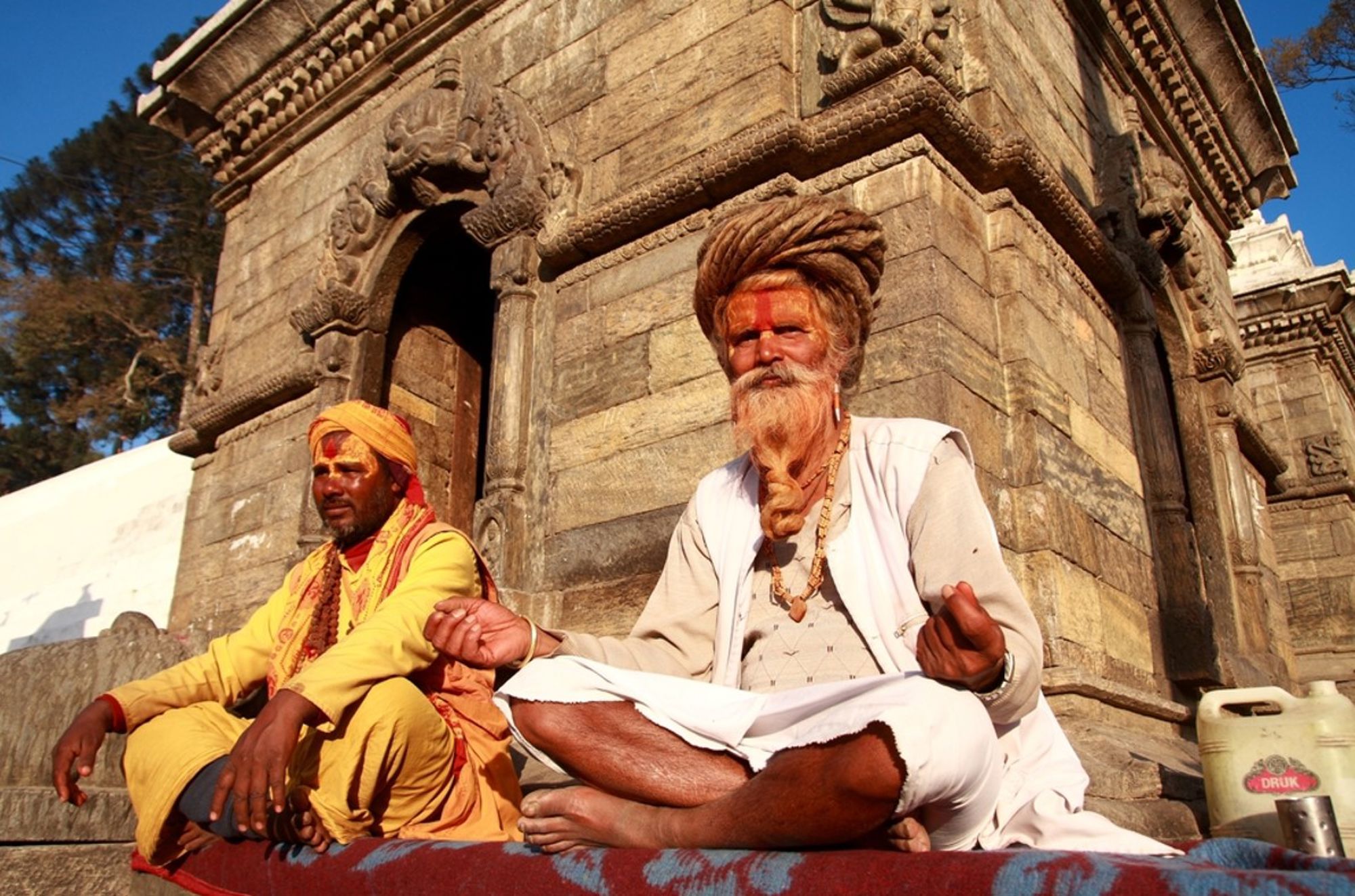 Sadhu’s mediteren bij een tempel in Nepal, zittend op een kleed in de zon.
